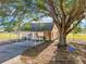 Back of home featuring shaded carport, yard with swing and mature tree at 4635 Brantley Rd, Groveland, FL 34736
