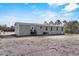Single-story home with gray siding, black stairs, well-maintained lawn, and multiple windows under a blue sky at 48 Oakridge Dr, Frostproof, FL 33843