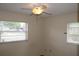 Well-lit bedroom featuring a ceiling fan, two windows, and hardwood flooring at 5177 Edwina St, Orlando, FL 32811