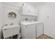 Functional laundry room with white washer, dryer, utility sink, and overhead cabinets at 5726 Leboeuf Ln, The Villages, FL 32163