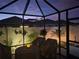 Enclosed patio with a view of the backyard, decorative wall art, and outdoor seating under the night sky at 5726 Leboeuf Ln, The Villages, FL 32163