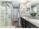 Bathroom with double sinks, granite countertops, vanity mirror, walk-in shower, and wooden floors at 6342 Whittle Ct, The Villages, FL 32163