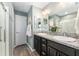 Bathroom with double sinks, granite countertops, vanity mirror, walk-in shower, and wooden floors at 6342 Whittle Ct, The Villages, FL 32163
