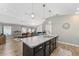Open kitchen featuring island with dark cabinets, stainless steel dishwasher, and views of the living and dining areas at 6342 Whittle Ct, The Villages, FL 32163