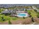 Aerial view of a community pool with palm trees, surrounded by lush green lawns and a community clubhouse at 6342 Whittle Ct, The Villages, FL 32163