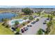 Aerial view of a community pool, clubhouse, and parking area with golf carts near a lake at 6342 Whittle Ct, The Villages, FL 32163