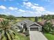 Aerial view of home with golf course backdrop, lush landscaping, and brick driveway at 685 Winifred Way, The Villages, FL 32162