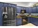 Close up of a stylish kitchen with blue cabinets and stainless steel appliances at 685 Winifred Way, The Villages, FL 32162