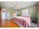 Cozy bedroom with light green walls, hardwood floors, ceiling fan, and a comfortable bed at 7115 Lake Ola Dr, Mount Dora, FL 32757