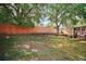 Large backyard with well-maintained lawn, tall wooden fence, and screened porch in the distance at 831 Whisper Sound, Minneola, FL 34715