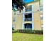 Condo exterior with screened balcony, yellow paint, and manicured landscaping at 8815 Dunes Ct # 105, Kissimmee, FL 34747