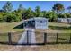 Gated single-story home with a covered porch, surrounded by mature trees and a fenced yard at 8901 Se 144Th Ln, Summerfield, FL 34491