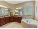 Bright bathroom with a large soaking tub, tile floor, and a spacious double vanity with dark cabinets at 1001 Harmony Ln, Clermont, FL 34711