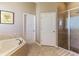 Bathroom featuring a soaking tub, shower with glass doors, and two white doors, offering convenience and style at 1001 Harmony Ln, Clermont, FL 34711