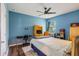 Bright bedroom with blue walls, a ceiling fan, a study desk, and hardwood floors, creating a comfortable space at 1001 Harmony Ln, Clermont, FL 34711