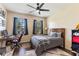 Cozy bedroom with dark wood floors, a comfortable bed, a ceiling fan, and a functional desk at 1001 Harmony Ln, Clermont, FL 34711