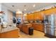 Bright kitchen with stainless steel fridge, granite counters, island cooktop, and plentiful wooden cabinets at 1001 Harmony Ln, Clermont, FL 34711