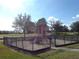 Community playground with climbing structure inside a metal fenced area with a safety surface at 1001 Harmony Ln, Clermont, FL 34711