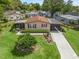 Inviting single-story home featuring a well-manicured lawn, mature landscaping and a screened in porch at 1003 Parker Pl, Lady Lake, FL 32159