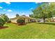 Lush green backyard with mature trees and a manicured lawn, complemented by the home's exterior at 10460 Silver Maple Ave, Oxford, FL 34484
