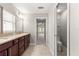 Bright bathroom featuring double vanity with granite counters, tile flooring, and glass door shower at 10460 Silver Maple Ave, Oxford, FL 34484
