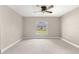 Spacious bedroom with neutral carpet, ceiling fan, and window overlooking the landscaped yard at 10460 Silver Maple Ave, Oxford, FL 34484