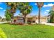 Well-maintained single-story home features lush green lawn, beautiful palms, brick paved driveway, and stone accents at 10460 Silver Maple Ave, Oxford, FL 34484