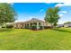 Well-maintained exterior showcasing a lush lawn, manicured landscaping, and an enclosed lanai at 10460 Silver Maple Ave, Oxford, FL 34484