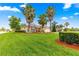 Well-manicured front yard with palm trees, lush green grass, and a charming home facade at 10460 Silver Maple Ave, Oxford, FL 34484