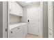 Functional laundry room with white washer, dryer, cabinets, and tiled floor at 10460 Silver Maple Ave, Oxford, FL 34484