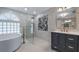 Modern bathroom showcasing a freestanding tub, glass shower, and elegant vanity with gold fixtures at 11024 Windchime Cir, Clermont, FL 34711