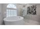 Stunning bathroom with a modern tub, glass-encased shower, and elegant marble tiling at 11024 Windchime Cir, Clermont, FL 34711