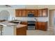 Close-up of the kitchen showcasing wooden cabinets, stainless steel oven, and a breakfast bar area at 11024 Windchime Cir, Clermont, FL 34711