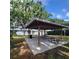 Community outdoor pavilion featuring wooden beams, concrete flooring, picnic tables, and a trash receptacle at 11024 Windchime Cir, Clermont, FL 34711