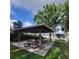 Community outdoor pavilion featuring wooden beams, concrete flooring, picnic tables, and a trash receptacle with a lake view at 11024 Windchime Cir, Clermont, FL 34711