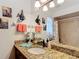 Bathroom featuring a granite countertop, framed mirror and a beige-tiled shower at 12110 Palmetto Ct, Dunnellon, FL 34432