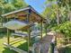 Modern boat dock featuring a covered boat lift and wooden walkway over the water at 12110 Palmetto Ct, Dunnellon, FL 34432