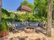Brick fire pit with seating area, lush tropical foliage, and views of the house at 12110 Palmetto Ct, Dunnellon, FL 34432