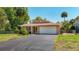 Charming one-story home with a well-manicured lawn, mature landscaping, and paved driveway at 12110 Palmetto Ct, Dunnellon, FL 34432