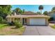 One-story home featuring a well-manicured lawn, mature landscaping and paved driveway at 12110 Palmetto Ct, Dunnellon, FL 34432