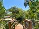 Wooden walkway leads down to the lake with lush landscaping and mature trees at 12110 Palmetto Ct, Dunnellon, FL 34432