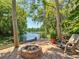 Outdoor fire pit area overlooking a serene lake surrounded by mature trees and lush foliage at 12110 Palmetto Ct, Dunnellon, FL 34432