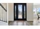 Elegant entryway featuring a black front door with decorative glass and hardwood floors, adjacent to a staircase at 12346 Lake Valley Dr, Clermont, FL 34711