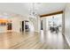 Bright living room with hardwood flooring, modern chandelier, and entry to dining area and adjacent kitchen at 12346 Lake Valley Dr, Clermont, FL 34711