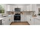 Stylish kitchen featuring white cabinets, modern appliances, and granite countertops at 1415 S Baton Dr, Deltona, FL 32725