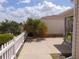View of the backyard with a white picket fence, palm tree, patio, and yellow and white house at 1420 Fairway St, The Villages, FL 32162