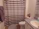 Bathroom featuring a brown striped shower curtain, granite countertops, potted plant and purple soap dispenser at 1420 Fairway St, The Villages, FL 32162