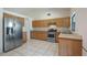 Open kitchen with stainless steel appliances, wood cabinets and bright tile flooring at 15918 Summit Ct, Clermont, FL 34711