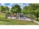 Community playground featuring a slide, swings, and climbing structures, surrounded by lush greenery and a secure fence at 15918 Summit Ct, Clermont, FL 34711