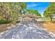 White home with covered parking and long driveway, surrounded by trees, on a sunny day at 16724 Highland Ave, Montverde, FL 34756